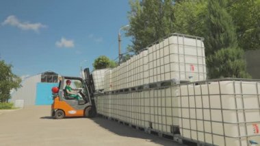 Forklift sıvıyla birlikte taşıyıcıyı kaldırır. Forklift konteynırı fabrikada taşıyor. Hava forklift işlemini aç