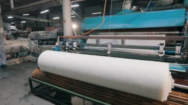 Büyük bir rulo sentetik kış sökücü. Syntepon üretim süreci. Endüstriyel iç.