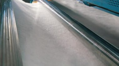 Sentetik kışlık konveyör hattında, yakın plan. Dokumasız malzeme üretimi için bir fabrika. Sentetik kış sökücü üretimi. Syntepon üretim süreci