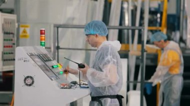 Fabrikadaki bir makinenin ön panelinde bir adam. Modern bir taşıyıcının kontrol panelinde çalışan bir işçi. Modern bir fabrikada çalışanlar..