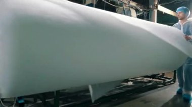 Sentetik kışlık konveyör hattında, yakın plan. Dokumasız malzeme üretimi için bir fabrika. Sentetik kış sökücü üretimi. Syntepon üretim süreci