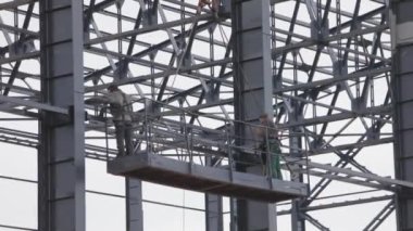 İşçiler metal yapılar boyuyor. İnşaat işi. Endüstriyel dış görünüş. İnşaatçılar binanın metal yapısını un ufak ediyorlar.