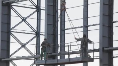 İşçiler metal yapılar boyuyor. İnşaat işi. Endüstriyel dış görünüş. İnşaatçılar binanın metal yapısını un ufak ediyorlar.