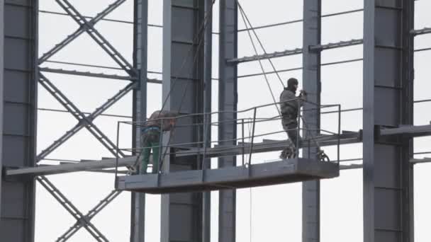 Dois trabalhadores de arranha-céus estão pintando uma estrutura de vassoura. Construtores a alta altitude — Vídeo de Stock