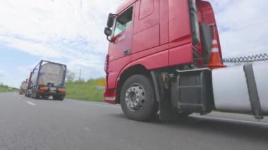 Kırmızı kamyon otoyol boyunca gidiyor. Bir grup kamyon otoyol boyunca gidiyor. Modern kamyonlar tanklarda sıvı kargo taşıyorlar