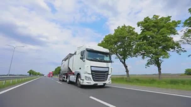 Ein Lastwagen mit Tankwagen fährt bei sonnigem Wetter über die Autobahn. Ein Lastwagenkonvoi fährt die Autobahn entlang. Weißer LKW fährt über die Autobahn. — Stockvideo