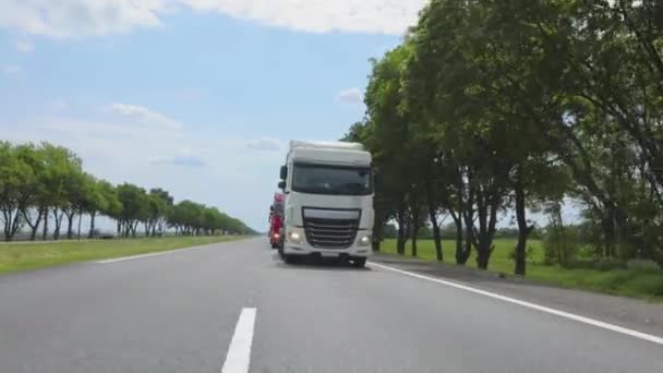 Weiße Lastwagen fahren die Autobahn entlang. Ein Lastwagen mit Tankwagen fährt bei sonnigem Wetter über die Autobahn. Ein Lastwagenkonvoi fährt über die Autobahn — Stockvideo