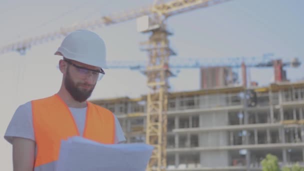 An engineer with a drawing at a construction site. Young engineer at a construction site. Engineer at a construction site — Stock Video