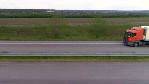 Lastbil på motorvägen utsikt från drönaren. Lastbil rider på modern motorväg runt grönt gräs ovanifrån. Godstransport. Logistik — Stockvideo