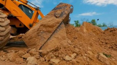 İnşaat alanında çalışma süreci. Traktör kovası yaklaş. Bir traktör inşaat alanında çukur kazıyor..