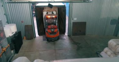 Bir forklift depoda çalışır. Depodaki bir forklift beyaz çantaları taşır. Forklift nakliye malları. Fabrika deposunda beyaz çantalar.