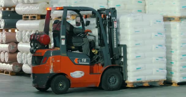 倉庫のフォークリフトは白い袋を動かす。フォークリフトは倉庫で働く。フォークリフトは貨物を輸送する。工場倉庫の白い袋 — ストック動画