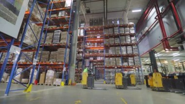 Fabrikanın deposunda özel ekipman var. Depoyu turlayan bir sürü forklift var. Modern yükleyiciler büyük bir depoda.