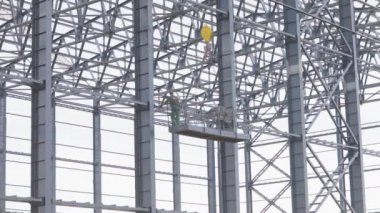 Builders paint the metal structure of the building from a pulverizer. Workers are painting metal structures. Construction work. Industrial exterior.