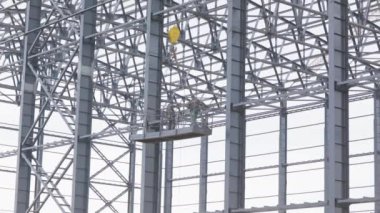 İki üst düzey işçi bir süpürge yapısını boyuyor. Yüksek irtifada yapıcılar