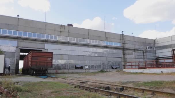 Een rode goederenwagen verlaat de werkplaats. Goederenwagons per spoor over het grondgebied van de fabriek — Stockvideo