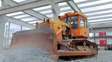 Buldozer toprağı düzleştiriyor. Buldozer yere moloz döküyor. İnşaat alanında büyük sarı bir buldozer. Sarı buldozer inşaat alanında çalışıyor..