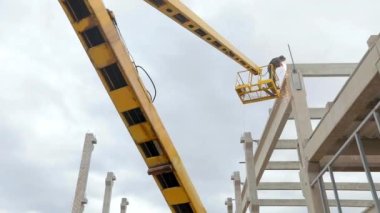 Vinçteki kaynakçı kaynak işi yapar. İnşaat alanında iş akışı. Kaynakçı yüksek irtifa çalışması yapıyor