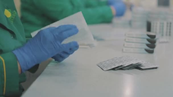 Заводські робітники спакують таблетки. Масковані працівники. Робочий процес на фармацевтичній фабриці — стокове відео