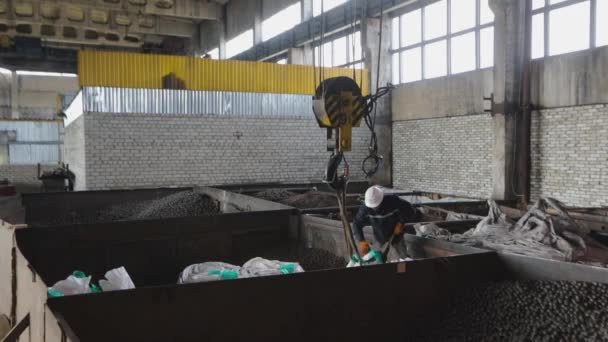 Großes Lager mit Metallkugeln. Ein Arbeiter verlädt Metallkugeln in Säcke. Arbeiter in der Fabrik für Metallkugeln — Stockvideo
