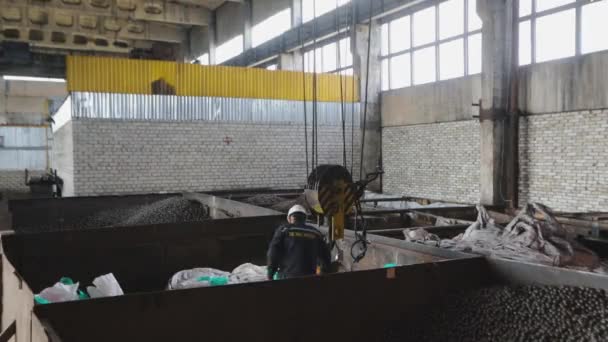 Grand entrepôt avec boules en métal. Un ouvrier charge des billes métalliques dans des sacs. Travailleur à l'usine de billes métalliques — Video