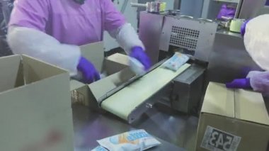 Kadınlar dondurmaları kutulara koyar. İşçiler kutulara dondurma koyarlar. Fabrika iş akışı