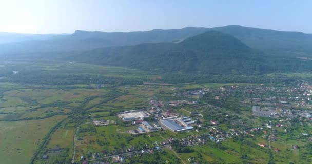 Een plant in een prachtig bergachtig gebied. Grote meubelfabriek tegen de achtergrond van bergen, uitzicht vanuit de lucht. Een moderne meubelfabriek in een pittoreske omgeving. — Stockvideo