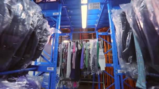 Skladiště s oblečením. Šaty visí v řadách ve skladišti. Oblečení ve skladišti v továrně. průmyslový interiér — Stock video