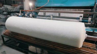 Sentetik kışlık konveyör hattında, yakın plan. Dokumasız malzeme üretimi için bir fabrika. Sentetik kış sökücü üretimi. Syntepon üretim süreci