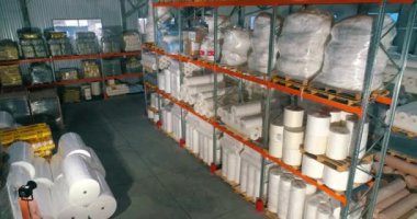 Dokumasız fabrikasındaki depo. Kumaşsız kumaş deposuna uçuş. Sentetik kış sarmalı büyük modern bir depo.