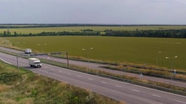 İnsansız hava aracının görüş alanında bir kamyon. Yeşil çimen manzaralı, modern otoyolda kamyon turu. Nakliye. Lojistik