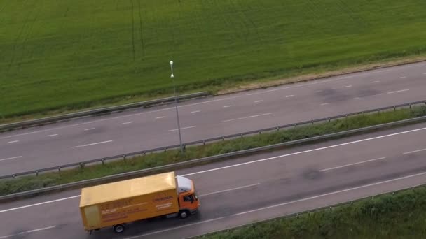 卡车在现代公路上环绕绿草的顶部景观行驶.从无人机看高速公路上的卡车. — 图库视频影像