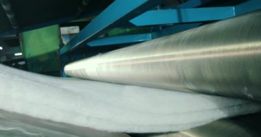 Sentetik kış sökücü üretimi. Sentetik kışlık konveyör hattında, yakın plan. Dokumasız malzeme üretimi için bir fabrika. Syntepon üretim süreci