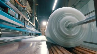Sentetik kışlık konveyör hattında, yakın plan. Dokumasız malzeme üretimi için bir fabrika. Sentetik kış sökücü üretimi. Syntepon üretim süreci