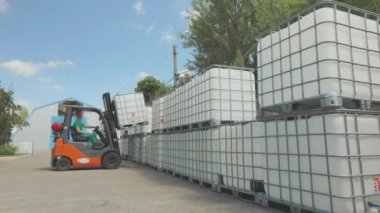 Forklift konteynırı fabrikada taşıyor. Forklift sıvıyla birlikte taşıyıcıyı kaldırır. Hava forklift işlemini aç