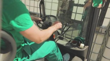 Bir işçi forklift kullanıyor. Forklift sürücüsü kolları hareket ettiriyor. Forklift denetim süreci