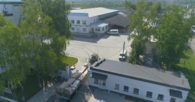 Traktör keresteleri fabrikanın arazisinden boş taşır. Traktör fabrikanın bölgesinden geçiyor. İnsansız hava aracından görüntüle.