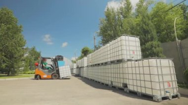 Forklift sıvıyla birlikte taşıyıcıyı kaldırır. Forklift konteynırı fabrikada taşıyor. Hava forklift işlemini aç.