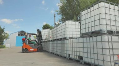 Forklift sıvıyla birlikte taşıyıcıyı kaldırır. Forklift konteynırı fabrikada taşıyor. Hava forklift işlemini aç.