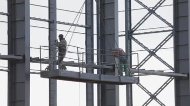 İşçiler metal yapılar boyuyor. İnşaat işi. Endüstriyel dış görünüş. İnşaatçılar binanın metal yapısını un ufak ediyorlar..