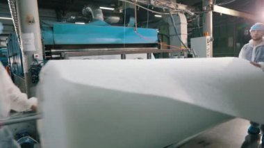 Baston olmayan malzemelerin üretimi yakın plan. Sentetik kışlık üretim fabrikası. Syntepon üretim süreci.