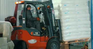 Depodaki bir forklift beyaz çantaları taşır. Bir forklift depoda çalışır. Forklift nakliye malları.