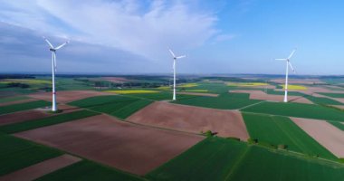 Tarım alanlarından ve rüzgar jeneratörlerinden oluşan hava panoramaları elektrik üretiyor. Alternatif rüzgar enerjisi elde etmek için modern teknolojiler. Hava görüntüsü. Alternatif enerji