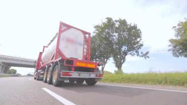 Kamyonlar yol boyunca gidiyor. Tank kamyonu olan bir kamyon otoyol boyunca yaklaşır. Tehlikeli malların nakliyesi.