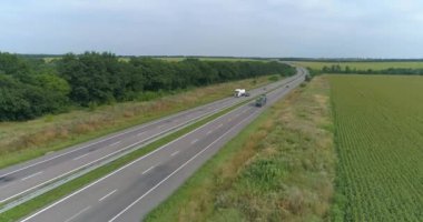 İnsansız hava aracının görüş alanında bir kamyon. Yeşil çimen manzaralı modern otoyolda kamyon turları.