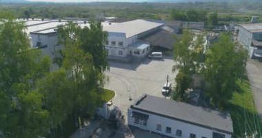 Traktör keresteleri fabrikanın arazisinden boş taşır. Traktör fabrikanın bölgesinden geçiyor. İnsansız hava aracından görüntüle.