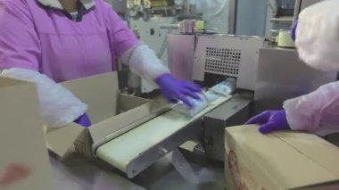 İşçiler kutulara dondurma koyarlar. Kadınlar dondurmaları kutulara koyar. Fabrika iş akışı.
