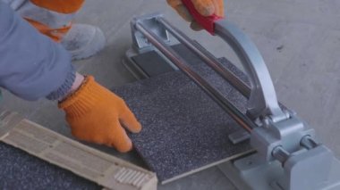 The builder works as a tile cutter. Tiler cuts tiles on a tile cutter.
