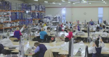 Bir terzi elbise fabrikasında çalışıyor. Tekstil üretimi. Çalışma süreci. Profesyonel ekipman dikiyorum..