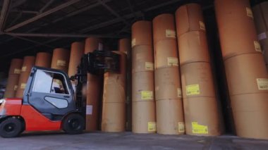Forklift büyük bir rulo kağıt taşıyor. Bir forklift fabrikada kağıt taşıyor. Duvar kağıdı fabrikasında yükleyici.